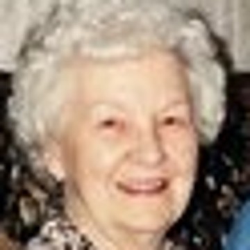 The small original: a white-haired grandmother smiling on a sofa